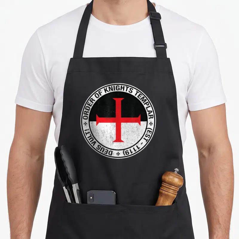 Tablier de cuisine noir avec un emblème circulaire noir blanc et rouge représentant les chevaliers templiers et la croix.
