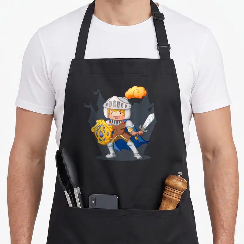 Tablier de cuisine noir avec illustration d'un jeune chevalier souriant tenant un bouclier et une épée devant un château.