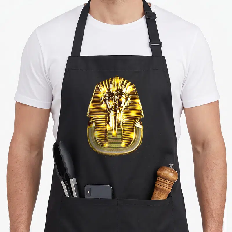 Tablier de cuisine noir avec un grand masque de pharaon Toutankhamon en or brillant au centre du torse.