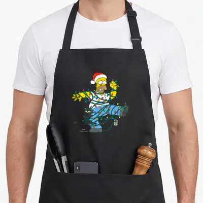 Tablier de cuisine noir avec Homer Simpson enchaîné par des guirlandes de Noël colorées et un chat noir.