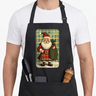 Tablier de cuisine noir avec illustration d'un Père Noël en tenue tartan portant un sac vert sur fond quadrillé.