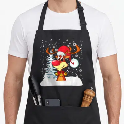 Tablier de cuisine noir avec illustration d'un renne au nez rouge coiffé d'un bonnet de Père Noël dans la neige.