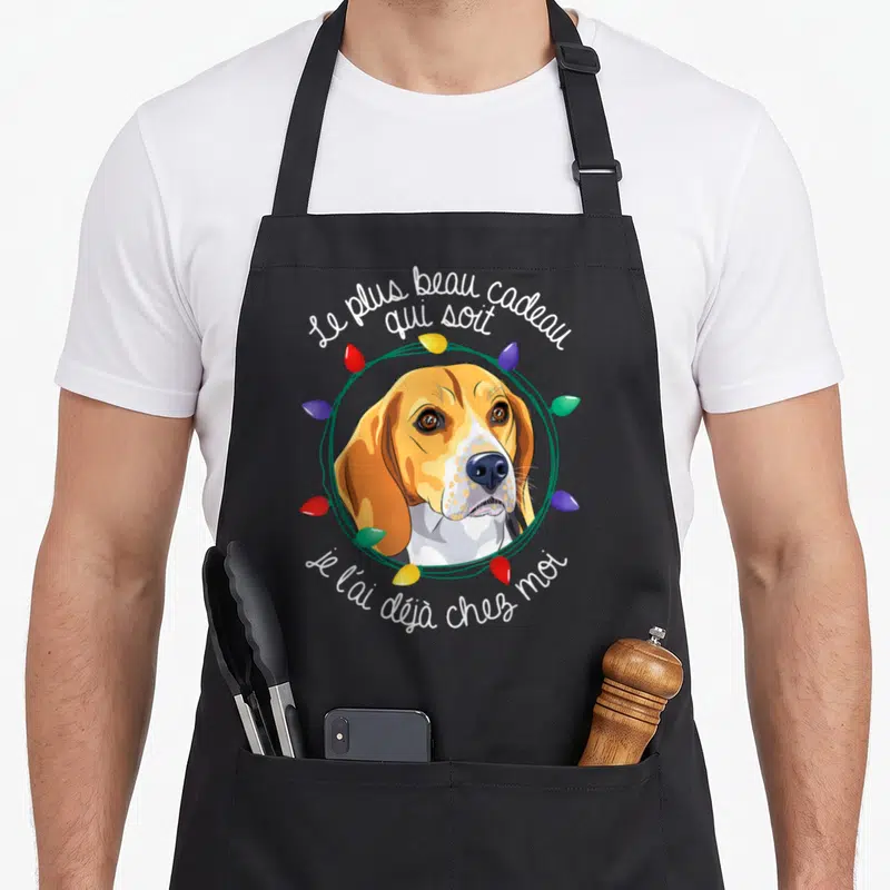 Tablier de cuisine noir avec illustration d'un beagle entouré de lumières colorées et texte festif.