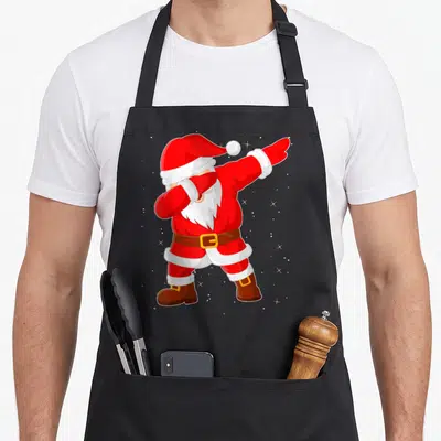 Tablier de cuisine noir avec illustration colorée d'un Père Noël en train de faire le dab sur fond gris poudré.