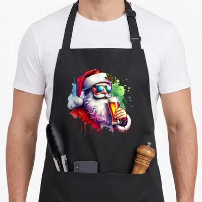 Tablier de cuisine noir avec un Père Noël aux lunettes bleues tenant une grande bière dorée sur fond de taches colorées.