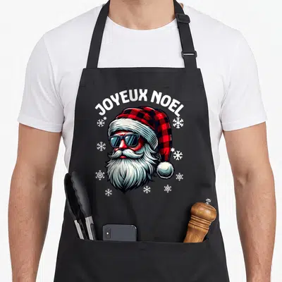 Tablier de cuisine noir avec illustration d'un Père Noël portant des lunettes de soleil et un bonnet à carreaux rouge et noir.