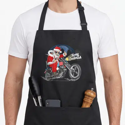 Tablier de cuisine noir avec illustration d'un Père Noël biker sur moto au drapeau américain et texte Merry Christmas.