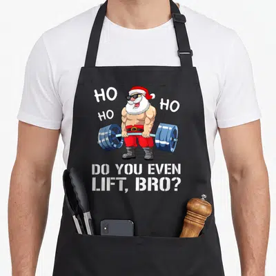 Tablier de cuisine noir avec un Père Noël musclé en train de soulever une barre bleue et les mots Do You Even Lift Bro imprimés en blanc.