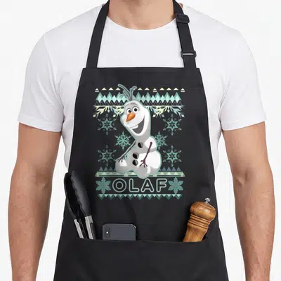 Tablier de cuisine noir avec Olaf souriant entouré de motifs de neige et de bleu clair sur fond gris uni.