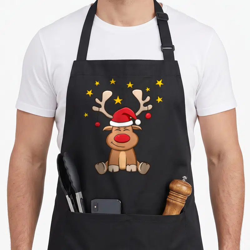 Tablier de cuisine noir avec illustration d'un ren Rudolf portant un chapeau de Père Noël et des étoiles jaunes.