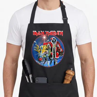 Tablier de cuisine noir avec illustration circulaire d'Eddie en costume de Père Noël montant un renne mécanique aux antennes dorées.