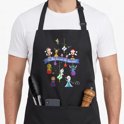 Tablier de cuisine noir avec Mickey, Elsa, Olaf et des décorations de Noël suspendues.