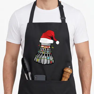 Tablier de cuisine noir avec un shuttle de badminton portant un bonnet de Père Noël et des lumières de Noël.