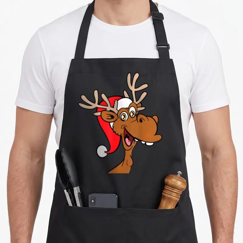 Tablier de cuisine noir avec un renne marron souriant portant une bonnette de Noël rouge et blanche.