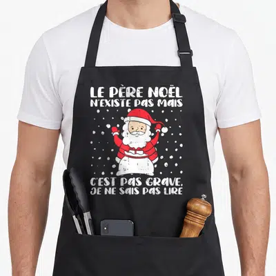 Tablier de cuisine noir avec illustration du Père Noël et texte humoristique en blanc sur fond sombre.