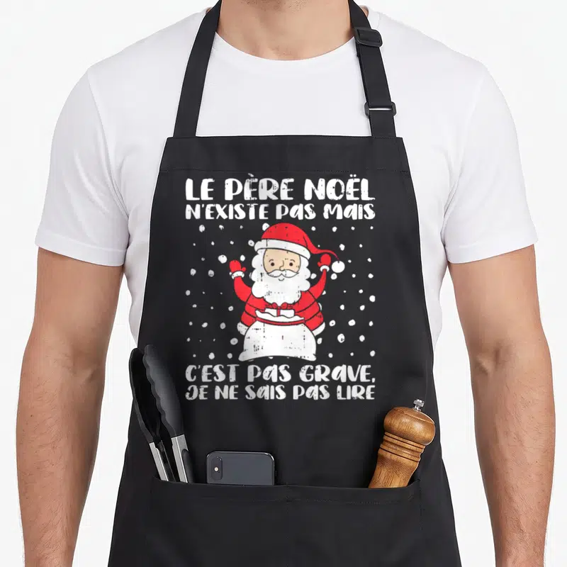 Tablier de cuisine noir avec illustration du Père Noël et texte humoristique en blanc sur fond sombre.