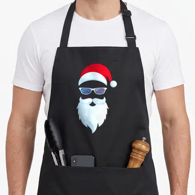 Tablier de cuisine noir avec illustration d'un Père Noël portant des lunettes de soleil blanches et une barbe fournie.