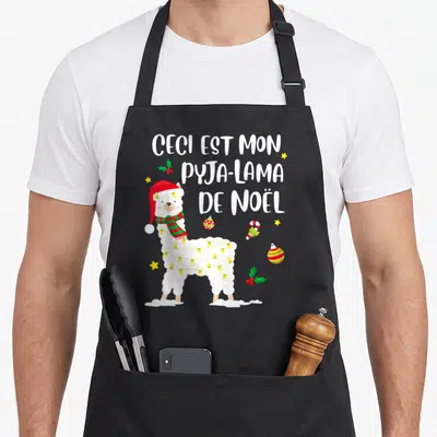 Tablier de cuisine noir avec illustration d'un lama portant une bonnette rouge et des guirlandes lumineuses jaunes.