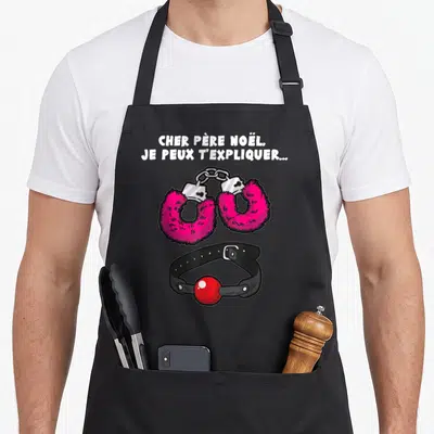 Tablier de cuisine noir avec menottes roses fourrées et collier à boule rouge imprimés au centre.