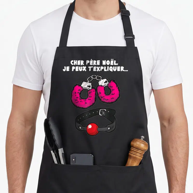 Tablier de cuisine noir avec menottes roses fourrées et collier à boule rouge imprimés au centre.