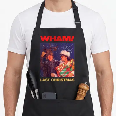 Tablier de cuisine noir avec une illustration de deux hommes en tenue hivernale tenant des cadeaux empaquetés.
