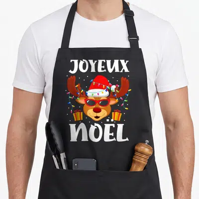 Tablier de cuisine noir avec un renne portant des lunettes de soleil et une casquette de Père Noël entourée de guirlandes lumineuses.