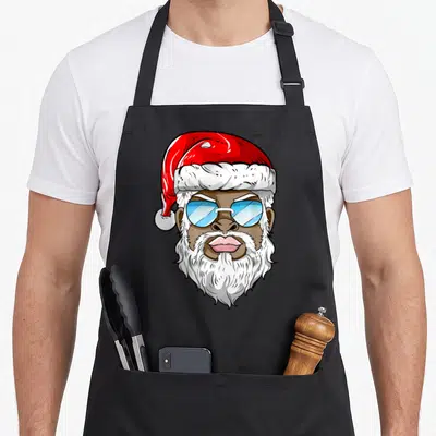 Tablier de cuisine noir avec illustration d'un Père Noël noir aux lunettes de soleil bleues et à la barbe blanche fournie.