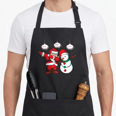 Tablier de cuisine noir avec illustration colorée d'un Père Noël et d'un bonhomme de neige en train de danser.