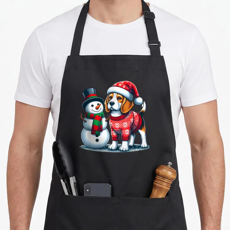 Tablier de cuisine noir avec un beagle en pull de Noël et un bonhomme de neige au chapeau haut de forme.