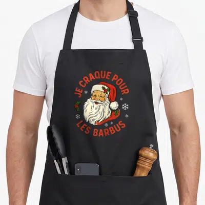 Tablier de cuisine noir avec illustration d'un Père Noël barbu et du texte Je craque pour les barbus en rouge.