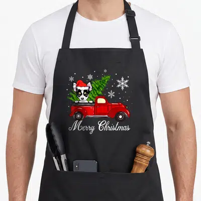 Tablier de cuisine noir avec illustration d'un chihuahua en bonnet de Père Noël dans un camion rouge portant un sapin de Noël