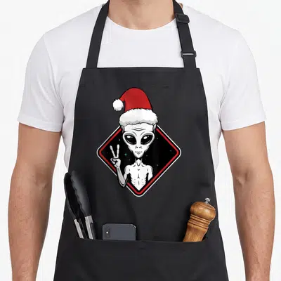 Tablier de cuisine noir avec illustration d'un alien portant un chapeau de Père Noël et faisant un signe de la paix.