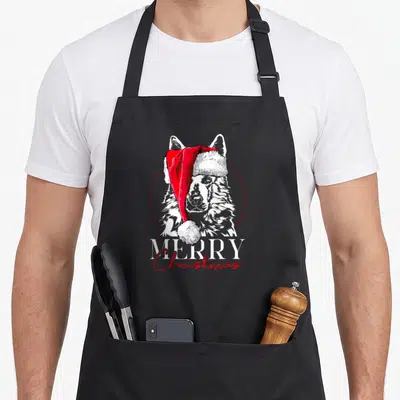 Tablier de cuisine noir avec illustration d'un chien Berger suisse portant un bonnet rouge et l'inscription Merry Christmas en bas du motif.