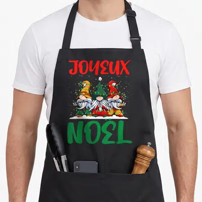 Tablier de cuisine noir avec trois gnomes de Noël entrelacés par des guirlandes lumineuses multicolores.