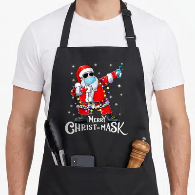Tablier de cuisine noir avec Père Noël masqué portant des lunettes de soleil et tenant du savon ainsi qu'un rouleau de papier toilette.
