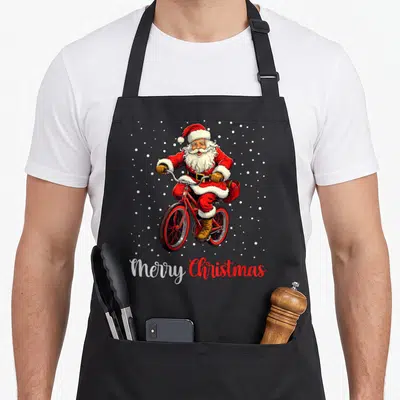 Tablier de cuisine noir avec un Père Noël en tenue de cycliste sur vélo rouge et l'inscription Merry Christmas en bas.