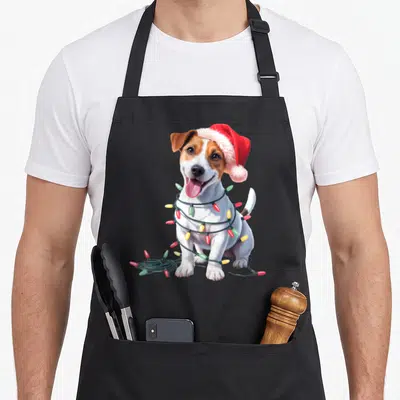Tablier de cuisine noir avec un chien Jack Russell portant un bonnet de Noël et des lumières festives autour du cou.