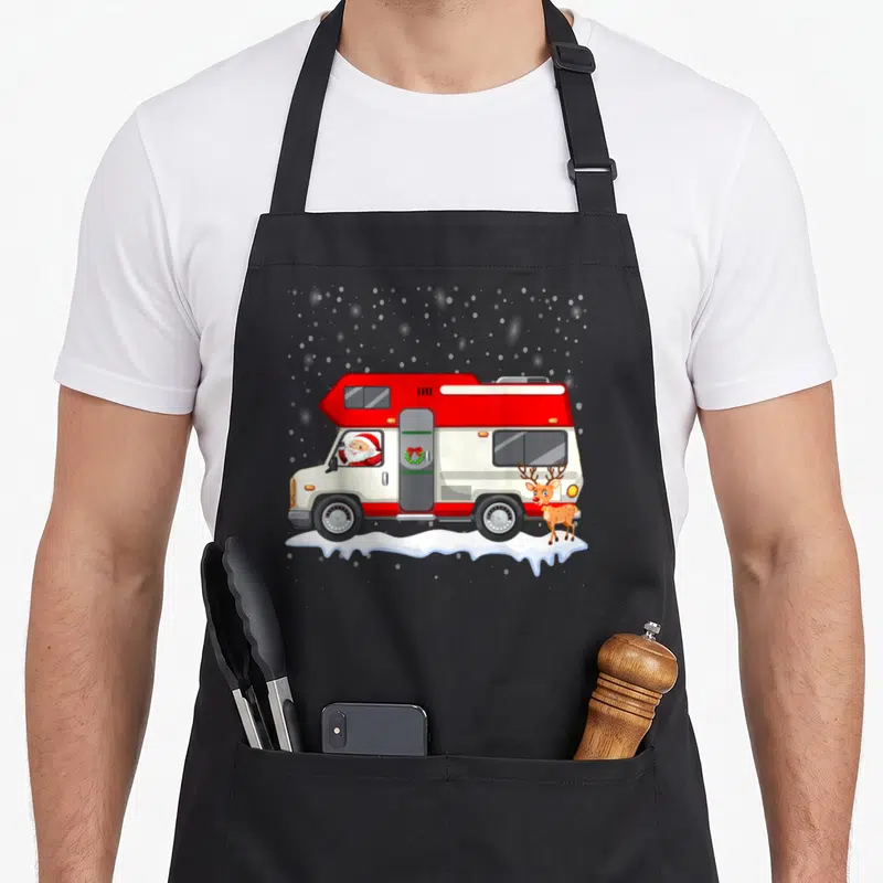 Tablier de cuisine noir avec illustration d'un camping-car rouge, du Père Noël au volant et d'un renard debout sur la neige.
