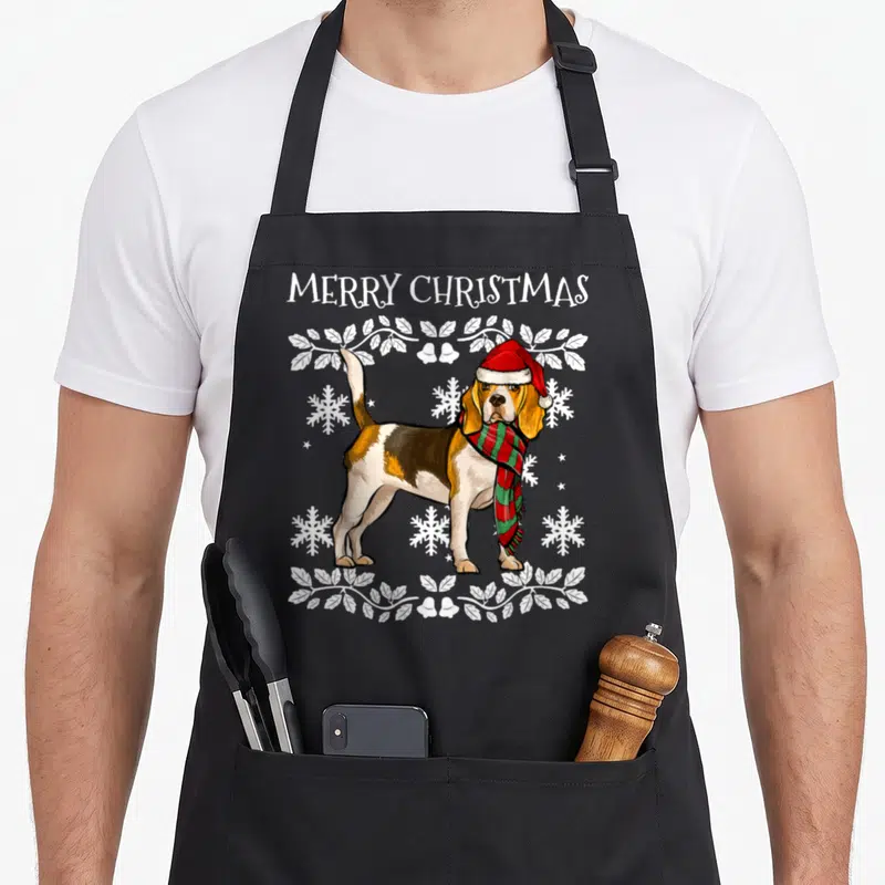Tablier de cuisine noir avec illustration d'un beagle en tenue de Noël entouré de motifs hivernaux blancs.