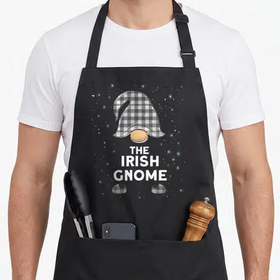 Tablier de cuisine noir avec illustration d'un nain irlandais au chapeau gris à carreaux et texte blanc THE IRISH GNOME sur fond étoilé.