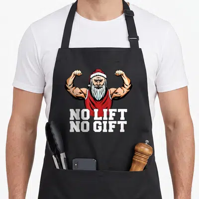 Tablier de cuisine noir avec illustration d'un Père Noël musclé et du texte No Lift No Cadeau en blanc.