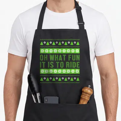 Tablier de cuisine noir avec motif Noël vert Oh What Fun It Is To Ride et motifs de flocons.