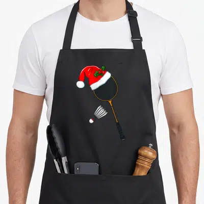 Tablier de cuisine noir avec une raquette de badminton portant un chapeau de Père Noël et un volant en dessous.