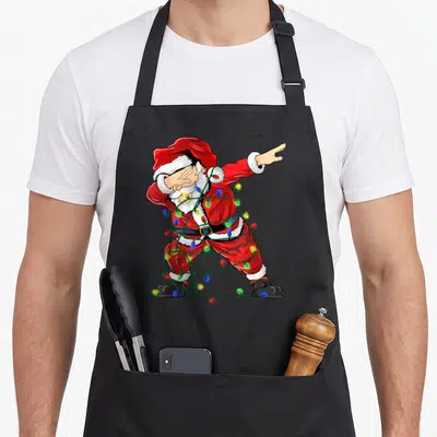 Tablier de cuisine noir avec illustration d'un Père Noël faisant le dabbing enroulé dans des lumières de Noël multicolores.