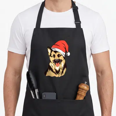 Tablier de cuisine noir avec illustration d'un chien de berger allemand portant un chapeau de Père Noël rouge et blanc.