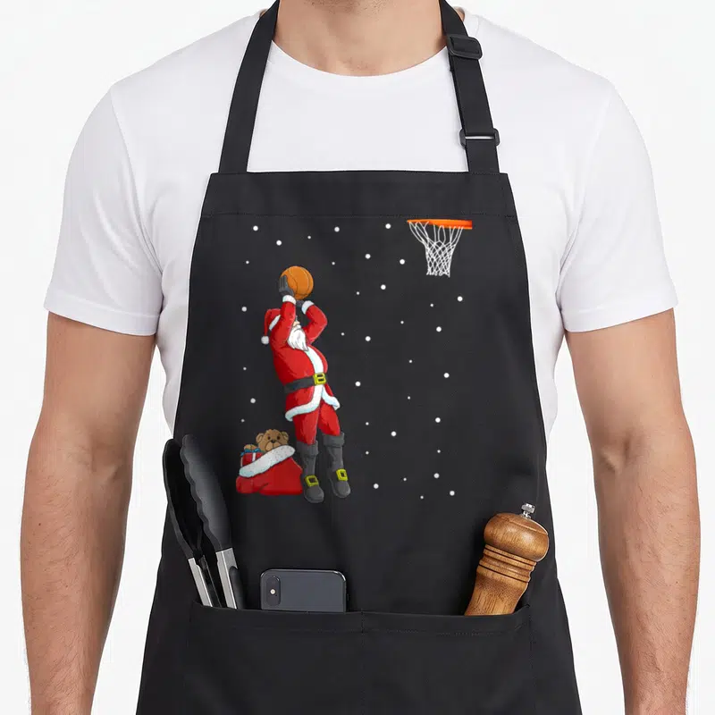 Tablier de cuisine noir avec le Père Noël tirant un panier de basket dans la neige.
