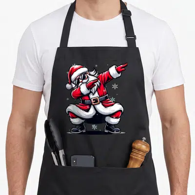 Tablier de cuisine noir avec illustration colorée d'un Père Noël effectuant la pose dab entouré de flocons de neige.
