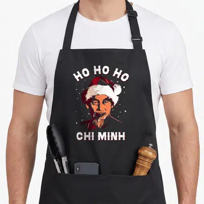 Tablier de cuisine noir avec portrait stylisé de Ho Chi Minh portant un bonnet de Père Noël et le texte Ho Ho Ho Chi MinH.