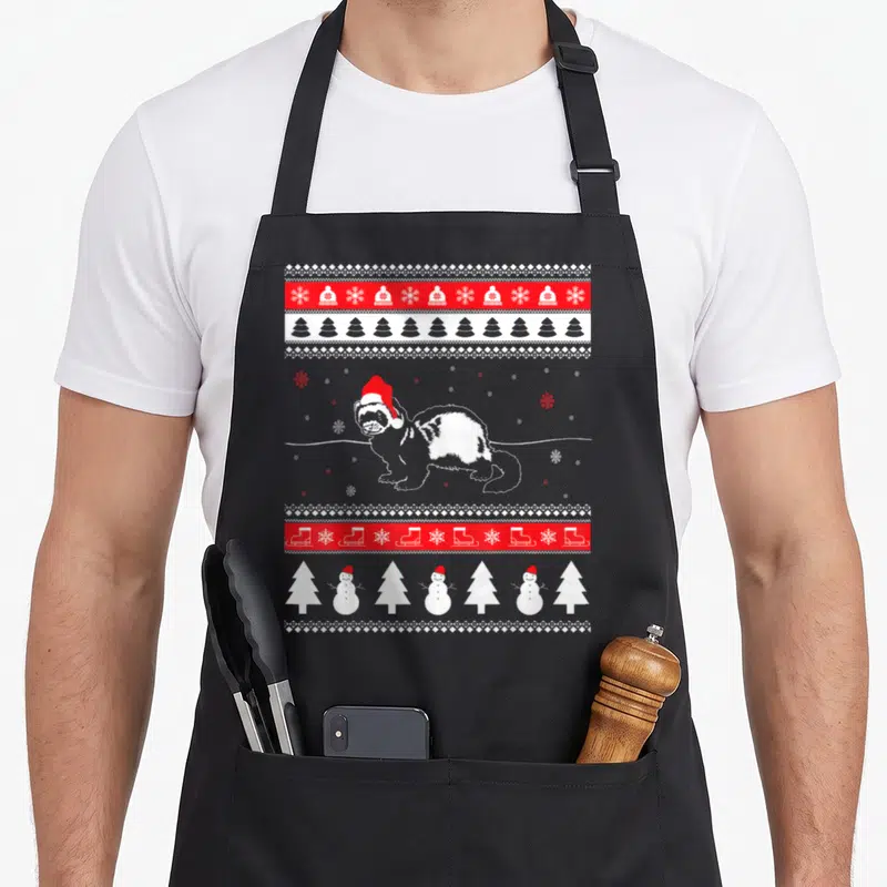 Tablier de cuisine noir avec illustration d'un furet en bonnet rouge encadré de motifs de Noël rouges et blancs.