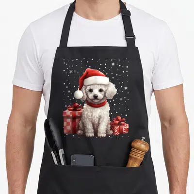 Tablier de cuisine noir avec un chiot caniche blanc coiffé d'un bonnet rouge et des cadeaux empaquetés.